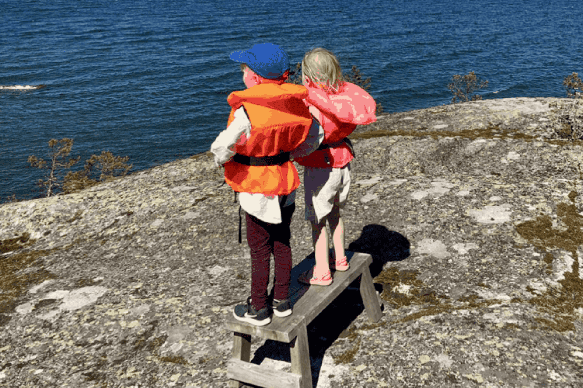 Kaksi lasta meren äärellä pelastusliiveissä.